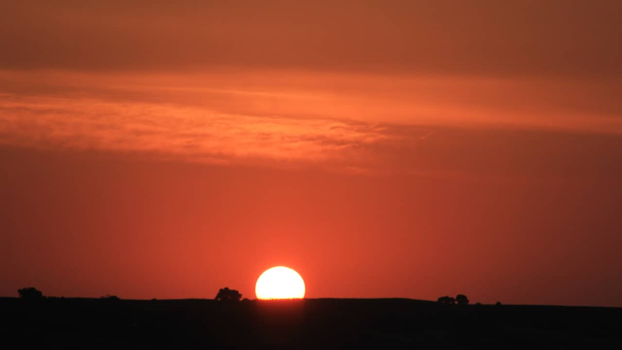 Bright orange sky with sun rising on horizon