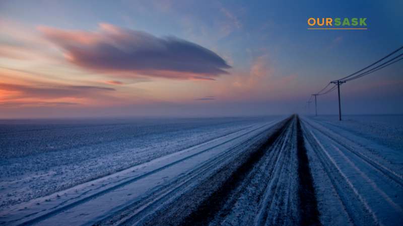 Snow covered open prairie and road with power lines stretching into the distance