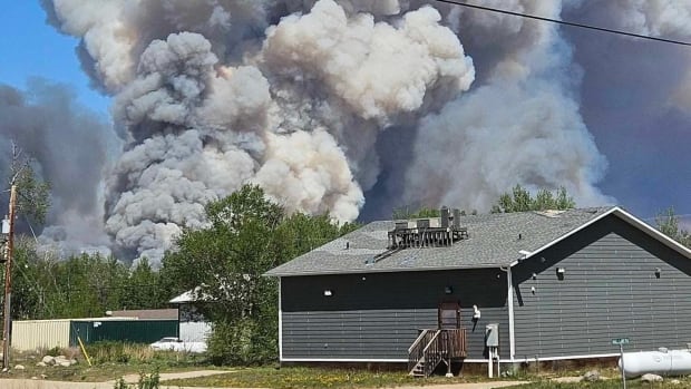 Smoke fills blue sky. A house is in front.